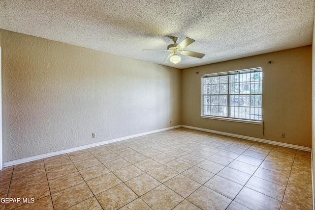 tiled empty room featuring baseboards, a textured wall, and a ceiling fan