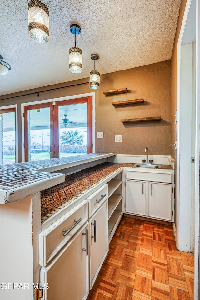 kitchen featuring open shelves, pendant lighting, dark countertops, a textured ceiling, and white cabinetry