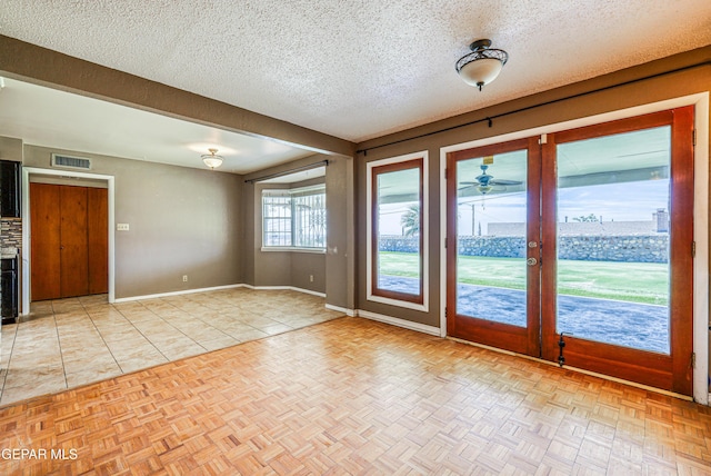 spare room with a textured ceiling, baseboards, visible vents, and ceiling fan