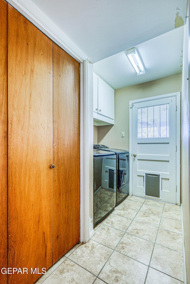 washroom featuring cabinet space, independent washer and dryer, light tile patterned flooring, and a fireplace
