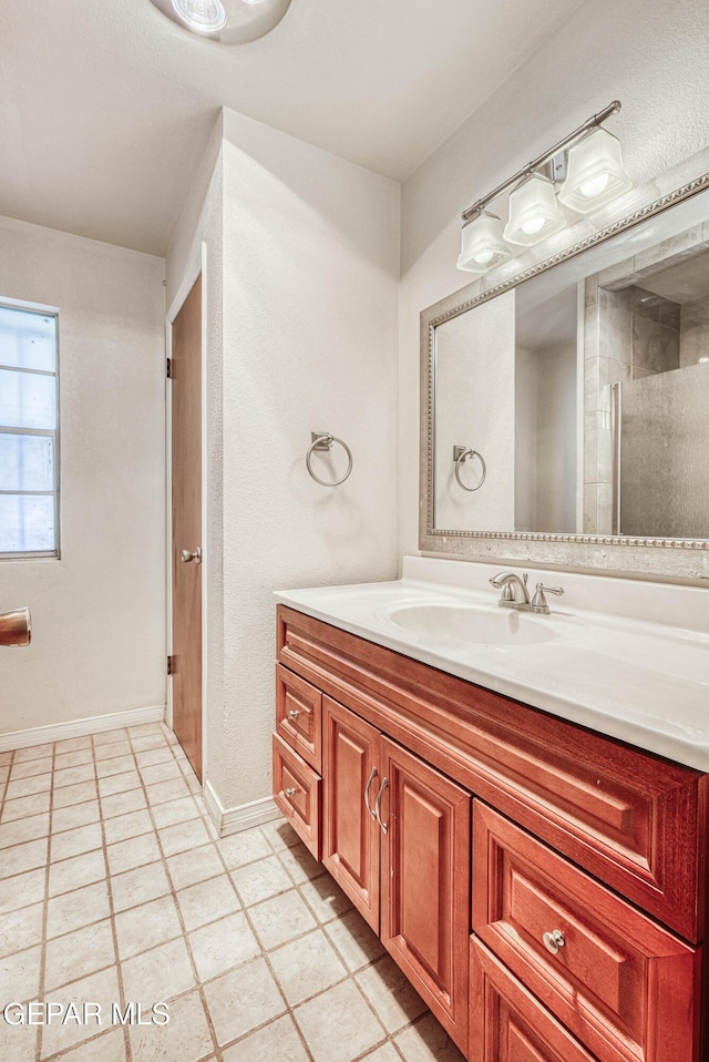 bathroom with vanity, a shower with door, baseboards, and tile patterned floors