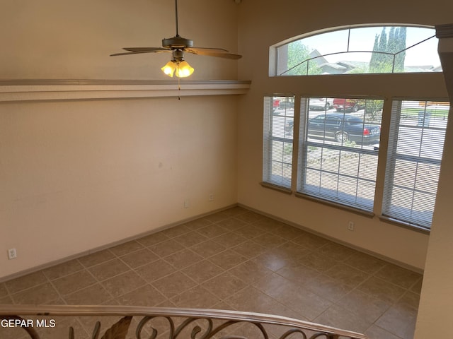 tiled spare room featuring baseboards and ceiling fan