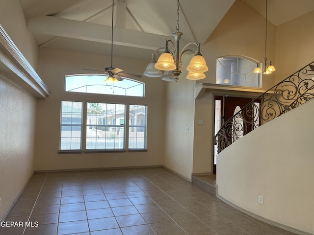 interior space with tile patterned flooring, ceiling fan with notable chandelier, and high vaulted ceiling