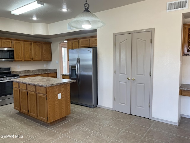 kitchen featuring visible vents, a kitchen island, baseboards, brown cabinets, and appliances with stainless steel finishes