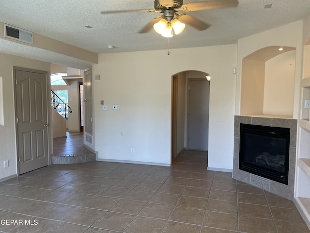 unfurnished living room with a textured ceiling, ceiling fan, visible vents, and baseboards
