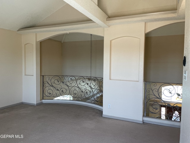carpeted empty room with baseboards, arched walkways, and vaulted ceiling