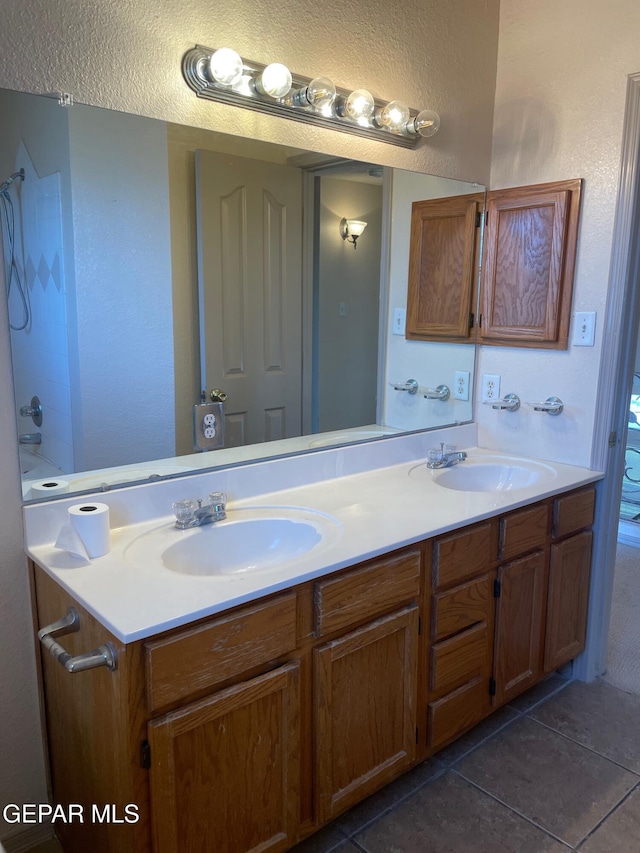 full bathroom with double vanity, a sink, and tile patterned floors