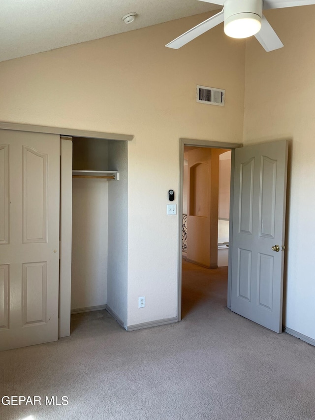 unfurnished bedroom with carpet floors, a closet, high vaulted ceiling, and visible vents