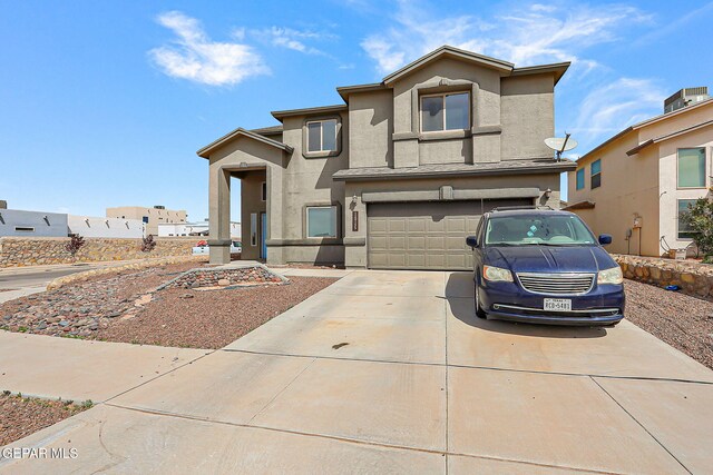 traditional-style house featuring stucco siding, a garage, and concrete driveway