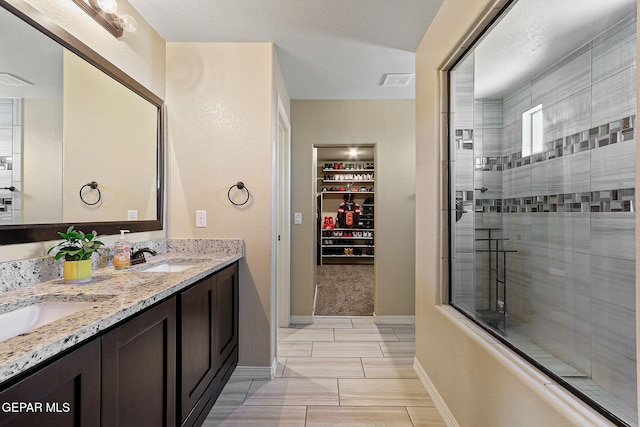 14717 Tierra Escape Ave, El Paso, TX 79938 - bathroom with a tile shower, double vanity, baseboards, and a walk in closet