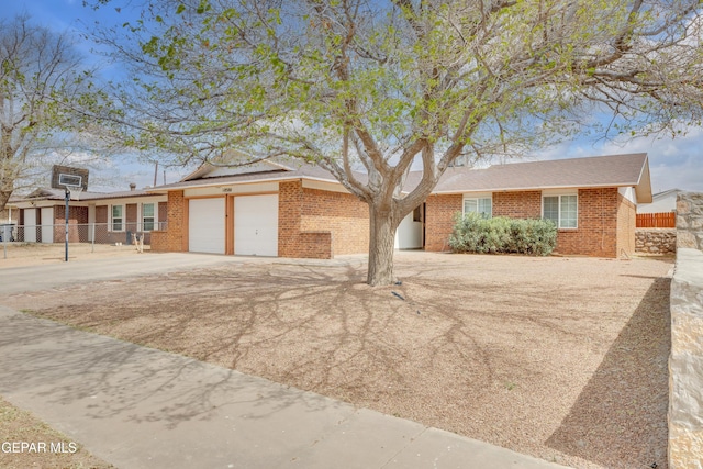 ranch-style home featuring brick siding, fence, a garage, and driveway