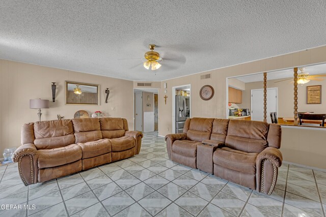 living area with visible vents, a ceiling fan, and a textured ceiling