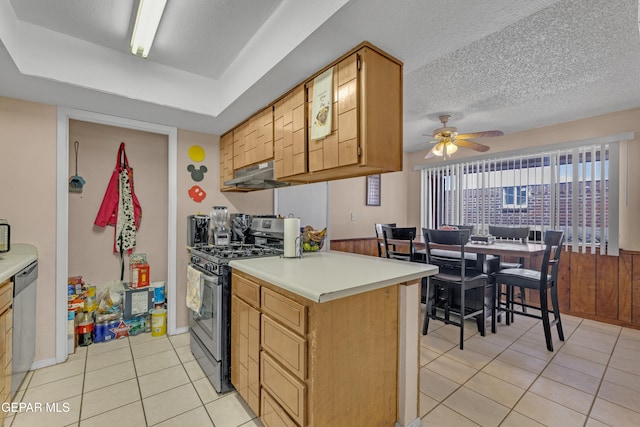 kitchen with ceiling fan, light tile patterned floors, a textured ceiling, under cabinet range hood, and stainless steel appliances