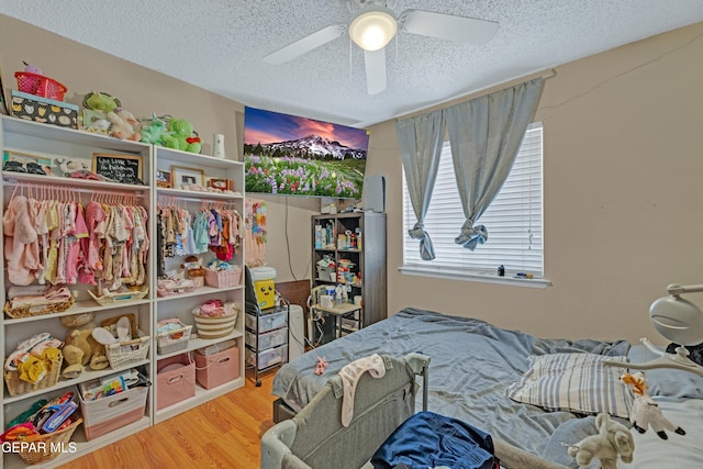 bedroom featuring a textured ceiling, wood finished floors, and a ceiling fan
