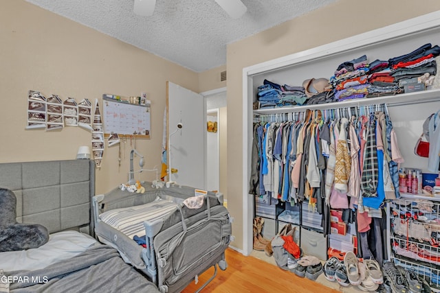bedroom featuring a closet, ceiling fan, a textured ceiling, and wood finished floors