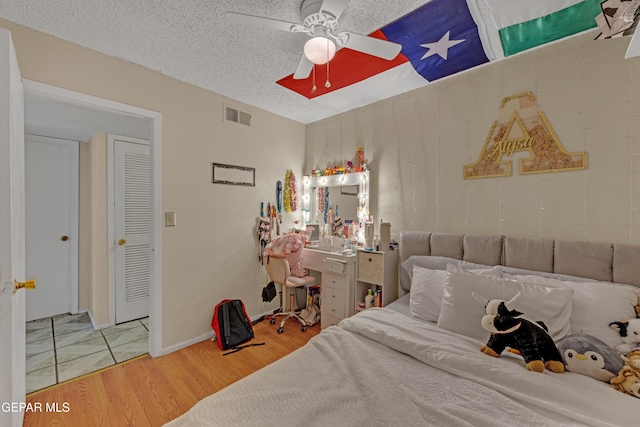 bedroom with visible vents, a textured ceiling, a ceiling fan, and wood finished floors