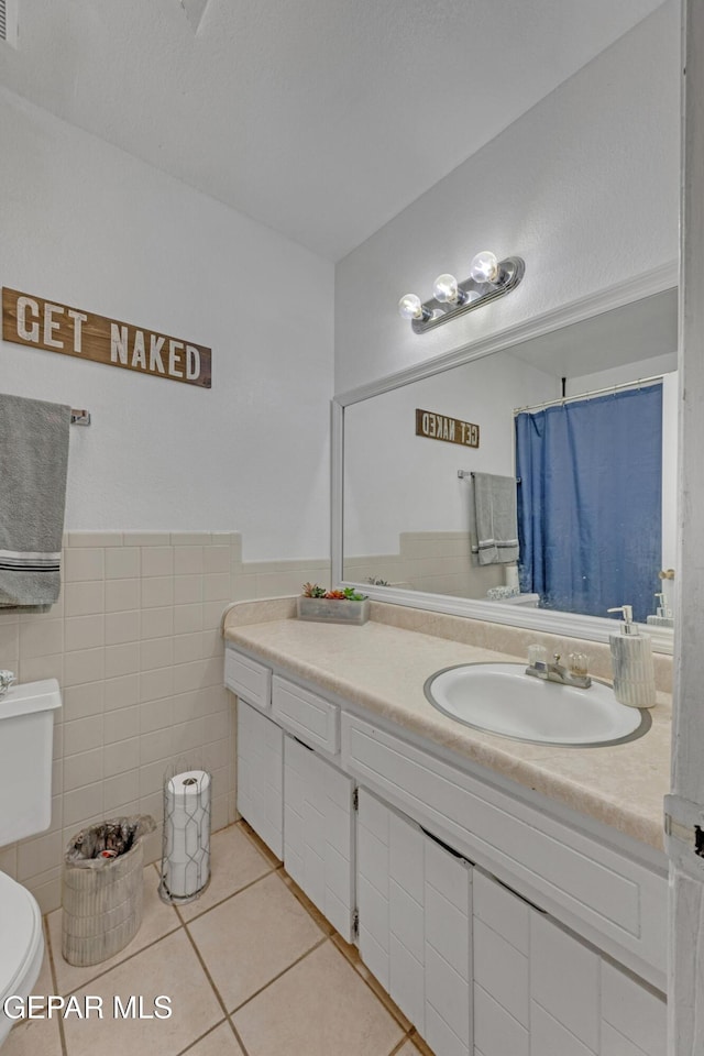 bathroom featuring tile walls, toilet, wainscoting, vanity, and tile patterned flooring