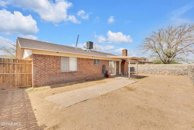 back of property with a patio, a chimney, brick siding, central AC unit, and fence