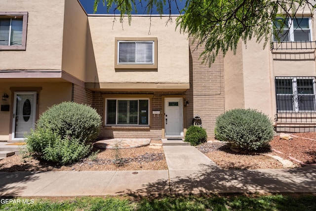 doorway to property with stucco siding and brick siding