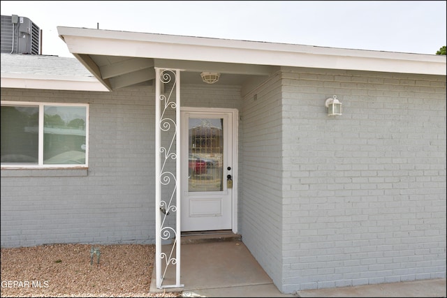 entrance to property featuring brick siding and central air condition unit