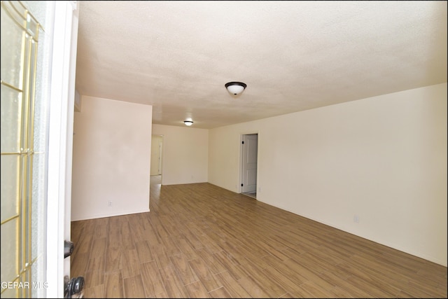 spare room with a textured ceiling and light wood finished floors
