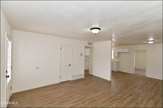 interior space with baseboards, visible vents, wood finished floors, and a textured ceiling