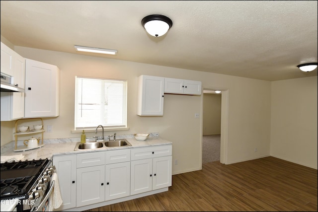 kitchen with light countertops, stainless steel gas stove, a sink, white cabinetry, and wood finished floors