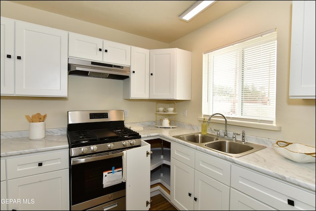kitchen with white cabinets, stainless steel range with gas cooktop, under cabinet range hood, and a sink