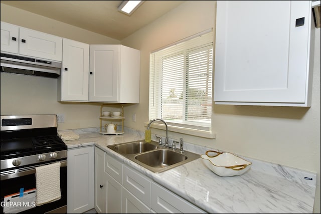 kitchen with light countertops, stainless steel range with gas stovetop, under cabinet range hood, a sink, and white cabinets