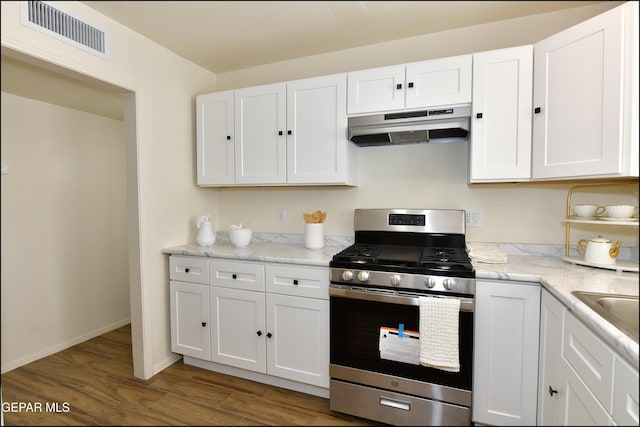 kitchen with white cabinetry, light wood-type flooring, under cabinet range hood, stainless steel gas range oven, and visible vents