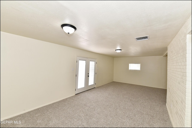 empty room with french doors, carpet floors, a textured ceiling, and visible vents