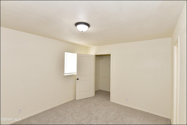 unfurnished bedroom with a closet, baseboards, and light colored carpet