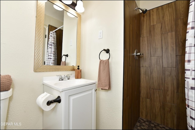 bathroom with a tile shower and vanity