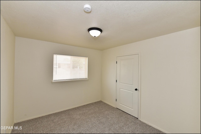 carpeted spare room with baseboards and a textured ceiling