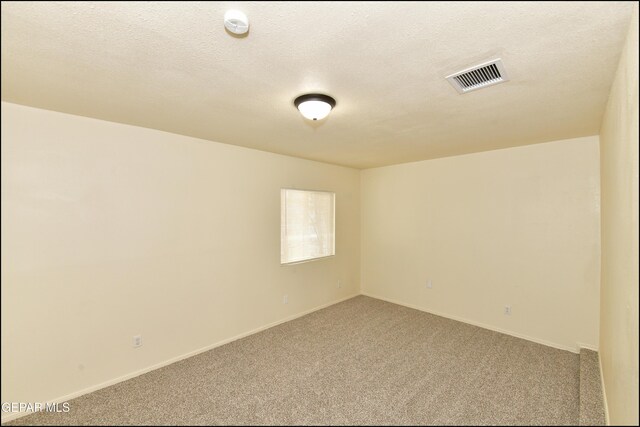 carpeted spare room with a textured ceiling, baseboards, and visible vents