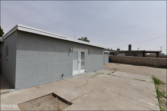 rear view of house with french doors, brick siding, fence, and a patio