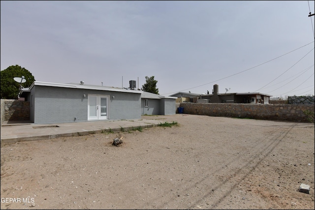 view of front of home with fence, brick siding, a patio area, and french doors