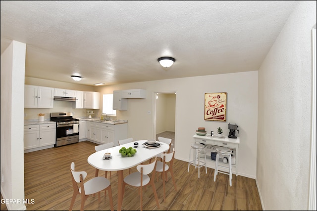 dining room with baseboards, a textured ceiling, and wood finished floors
