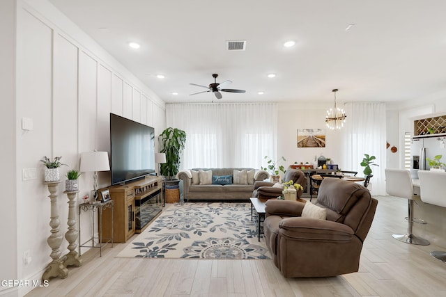 living area featuring visible vents, recessed lighting, light wood-style floors, and ceiling fan with notable chandelier