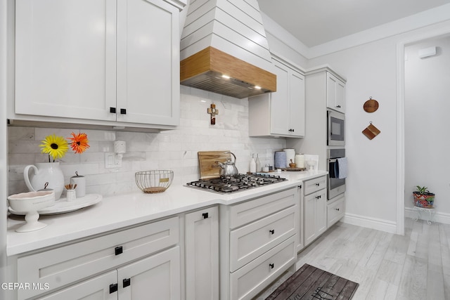 kitchen with custom range hood, backsplash, appliances with stainless steel finishes, and light countertops