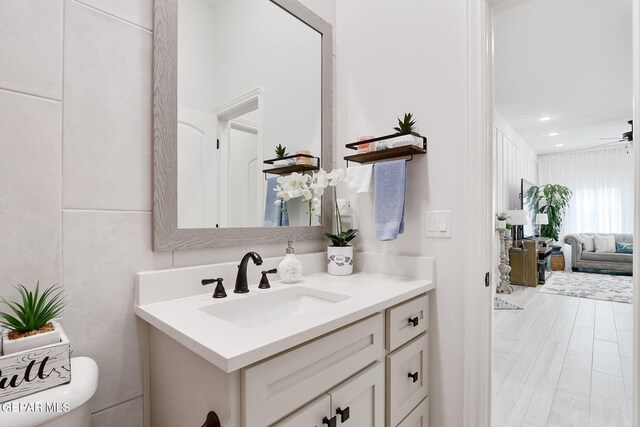 bathroom with toilet, ceiling fan, recessed lighting, vanity, and wood finished floors