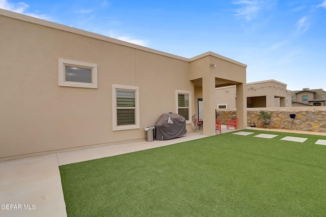 back of house with a yard, a patio area, and stucco siding