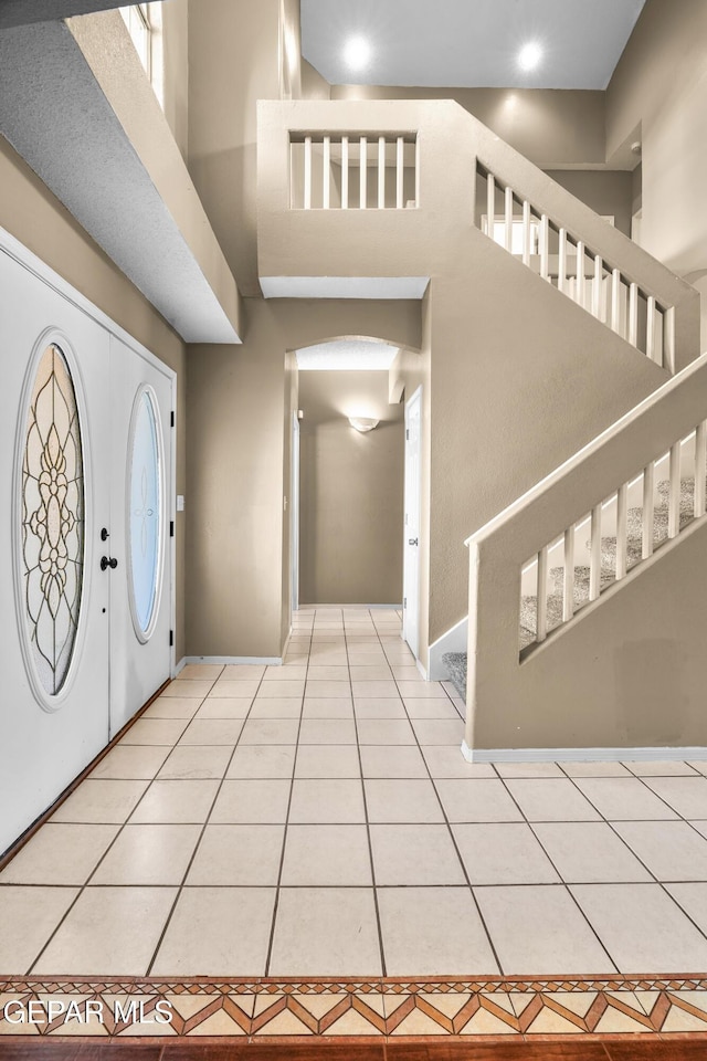 2987 Tierra Limon Dr, El Paso, TX 79938 - entrance foyer featuring a high ceiling, stairway, baseboards, arched walkways, and light tile patterned floors