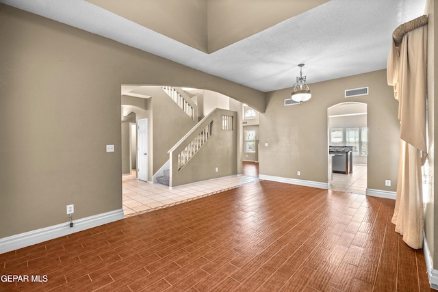 2987 Tierra Limon Dr, El Paso, TX 79938 - unfurnished living room with arched walkways, wood finished floors, baseboards, and stairs