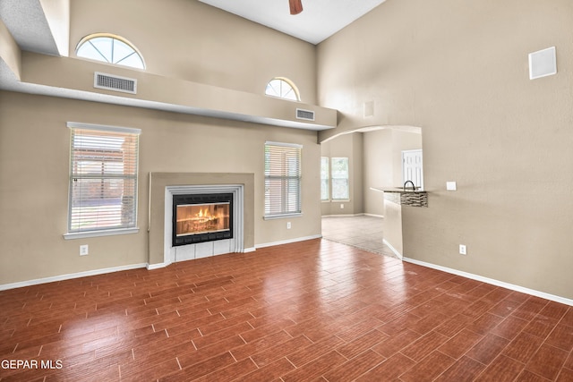 2987 Tierra Limon Dr, El Paso, TX 79938 - unfurnished living room with a ceiling fan, a towering ceiling, baseboards, wood finished floors, and a glass covered fireplace