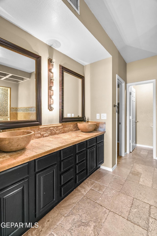 2987 Tierra Limon Dr, El Paso, TX 79938 - bathroom featuring stone tile flooring, double vanity, and baseboards