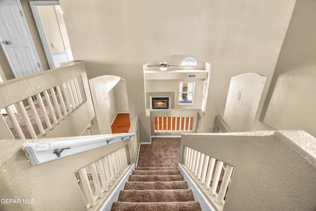 2987 Tierra Limon Dr, El Paso, TX 79938 - stairs featuring a ceiling fan, a glass covered fireplace, carpet floors, baseboards, and a high ceiling
