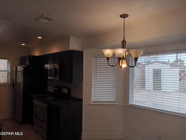kitchen with a notable chandelier, black range with electric cooktop, a textured ceiling, stainless steel microwave, and visible vents