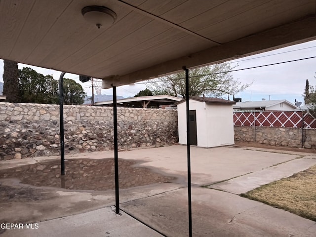 view of patio featuring an outbuilding, a fenced backyard, and a shed