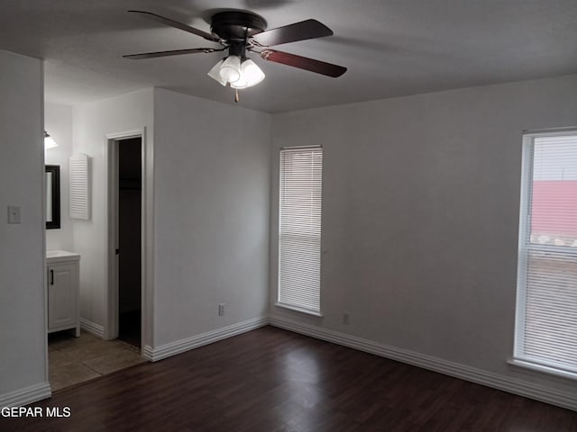 unfurnished bedroom with connected bathroom, baseboards, ceiling fan, and wood finished floors